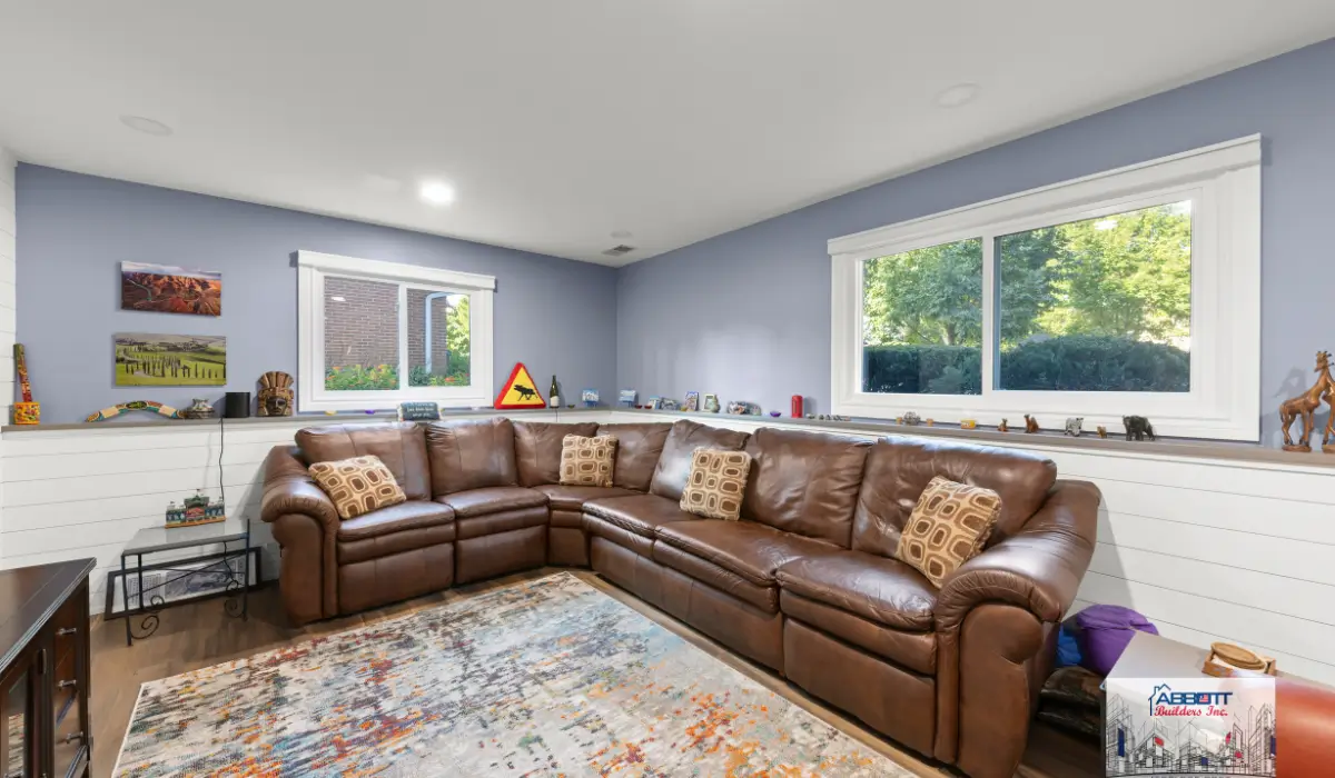Cozy upgraded unfinished basement converted into bright family living space with sectional seating and windows.