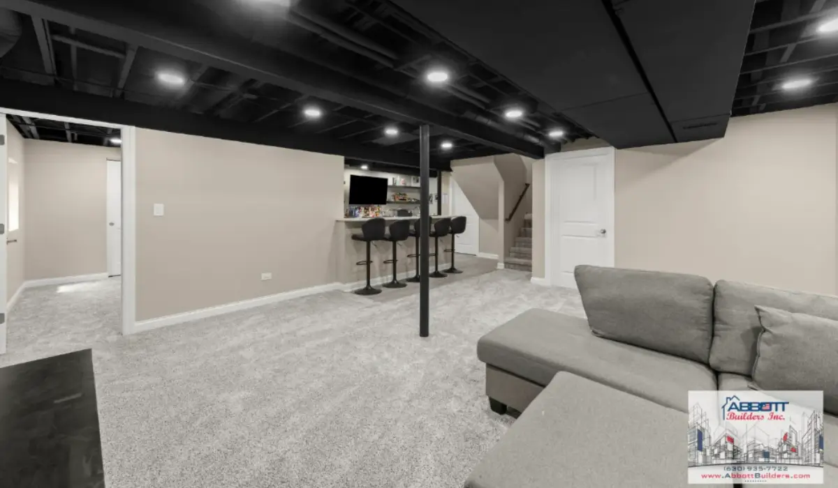 Basement design featuring an exposed ceiling, recessed lighting, structural columns, open seating, and separate bar area.